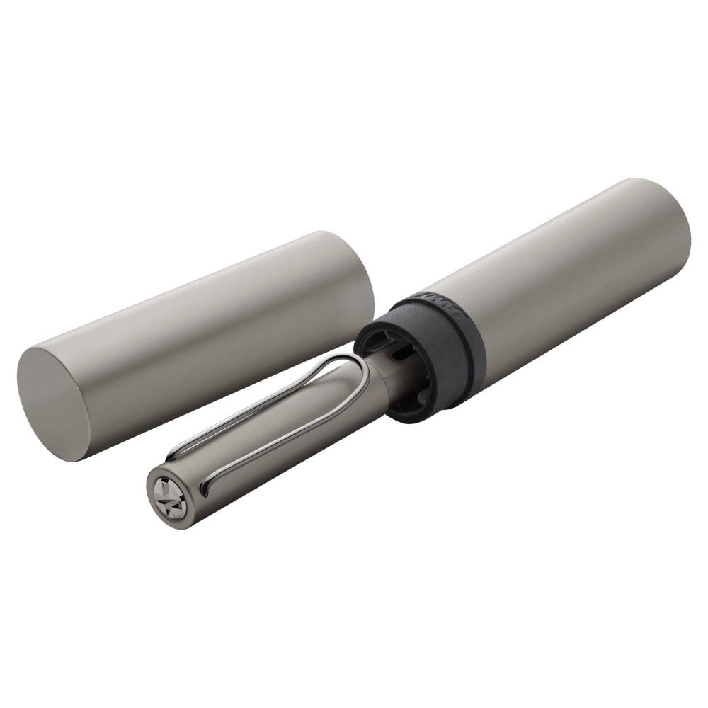 Un écrin ouvert contenant le stylo plume Lamy LX Ruthénium est posé sur un fond blanc. L'écrin présente sous forme cylindrique avec le logo de la marque, mettant en valeur la sophistication du produit.