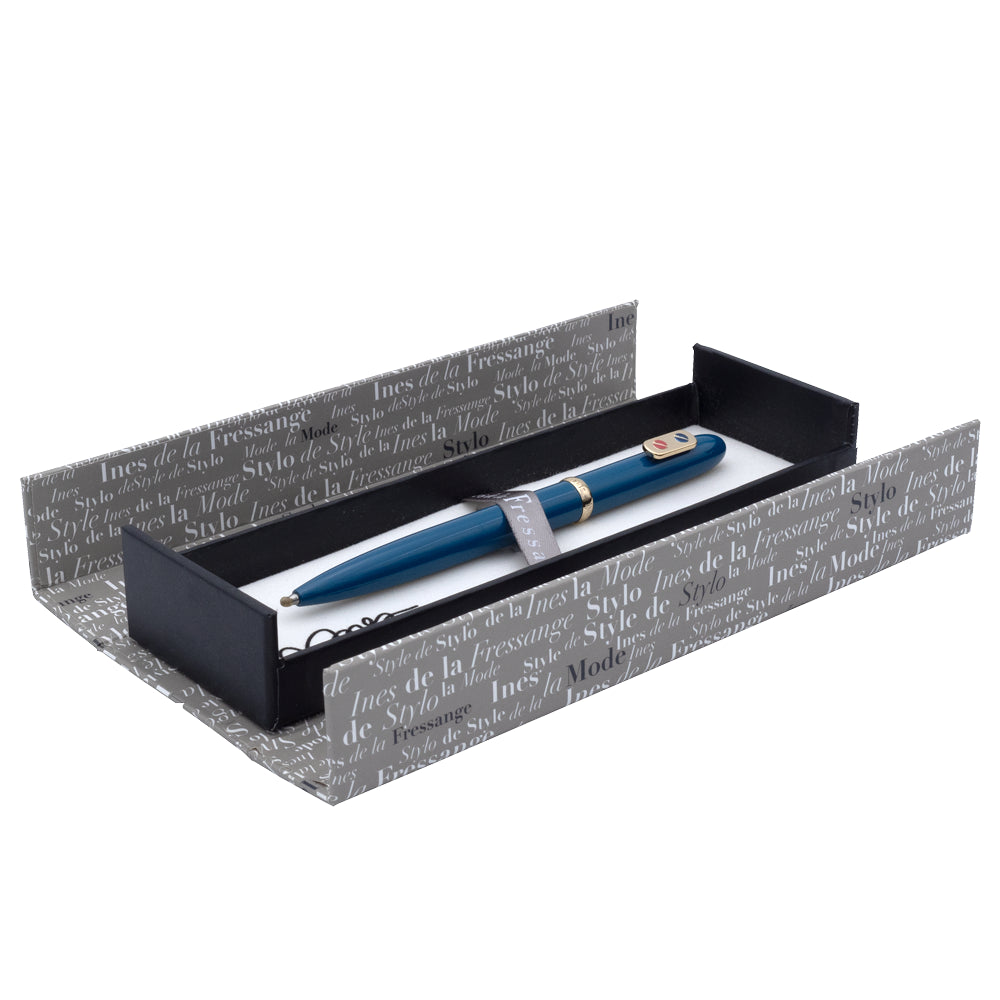 Un écrin ouvert du stylo roller bleu sarcelle avec attributs dorés de la marque Inès de la Fressange est posé sur un fond blanc. L'écrin est visible dans son intégralité, mettant en avant son design.