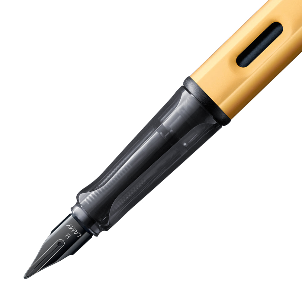 Gros plan sur la plume du stylo plume Lamy LX Aluminium Or. La plume en acier inoxydable de couleur noir est finement détaillée, tandis que la finition en aluminium doré du stylo ajoute une touche de sophistication à l'écriture fluide qu'il offre.