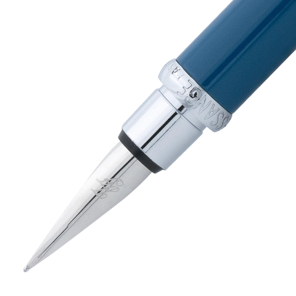 Un gros plan de la plume du stylo plume bleu sarcelle et fuchsia de la marque Inès de la Fressange. La plume est visible en détail, avec le stylo incliné à 45 degrés et le bouchon retiré.