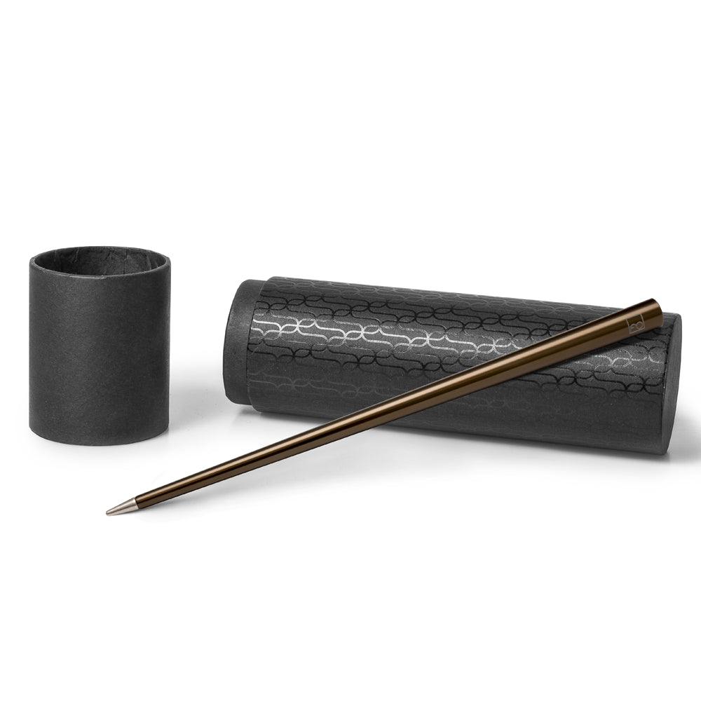 Stylo Forever Prima en bronze posé sur son écrin cylindrique noir avec des motifs, présenté sur un fond blanc. L'écrin cylindrique protège le stylo tout en mettant en valeur sa couleur bronze élégante et son design moderne.
