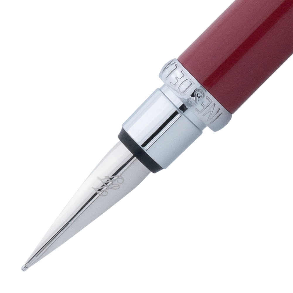 Un gros plan de la plume du stylo plume bordeaux rouge avec attributs chromes de la marque Inès de la Fressange. La plume est visible en détail, avec le stylo incliné à 45 degrés et le bouchon retiré, placé parallèlement au stylo, sur un fond blanc.