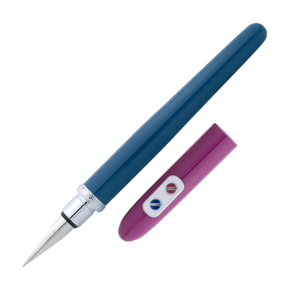 Un stylo plume bleu sarcelle et fuchsia de la marque Inès de la Fressange est incliné à 45 degrés, avec le bouchon retiré et placé parallèlement au stylo, sur un fond blanc.