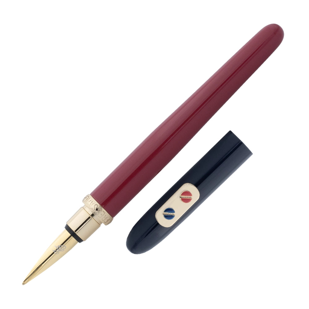 Un stylo plume bordeaux et bleu marine avec attributs dorés de la marque Inès de la Fressange est incliné à 45 degrés, avec le bouchon retiré et placé parallèlement au stylo, sur un fond blanc.